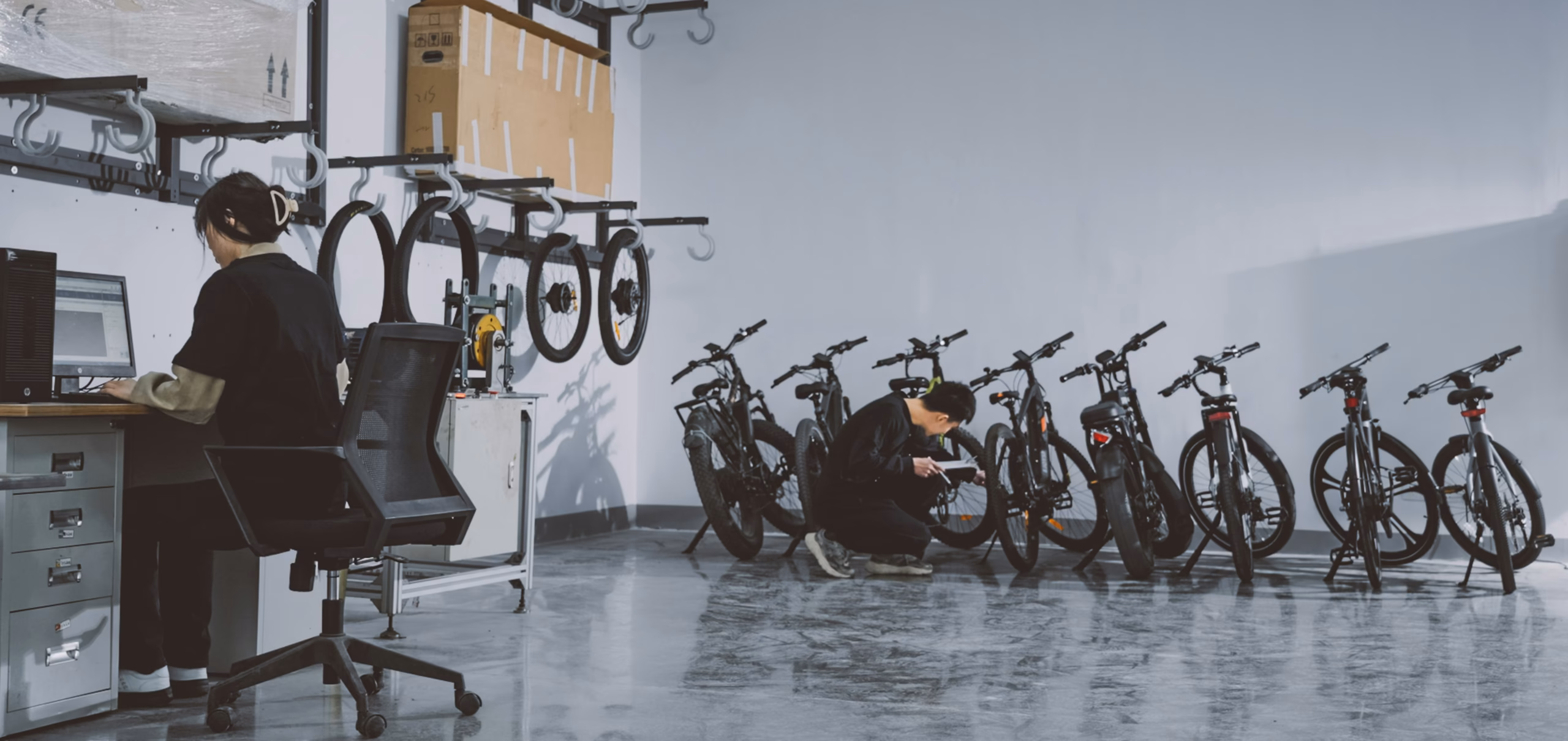 Chinese factory worker inspecting electric bicycles on production line in warehouse — illustrates Chinese outdoor gear supplier manufacturing capability and quality inspection