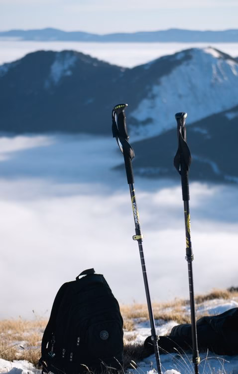 A pair of trekking poles and a black backpack standing upright beside each other, used to illustrate a backpack minimum order quantity guide for wholesale buyers.